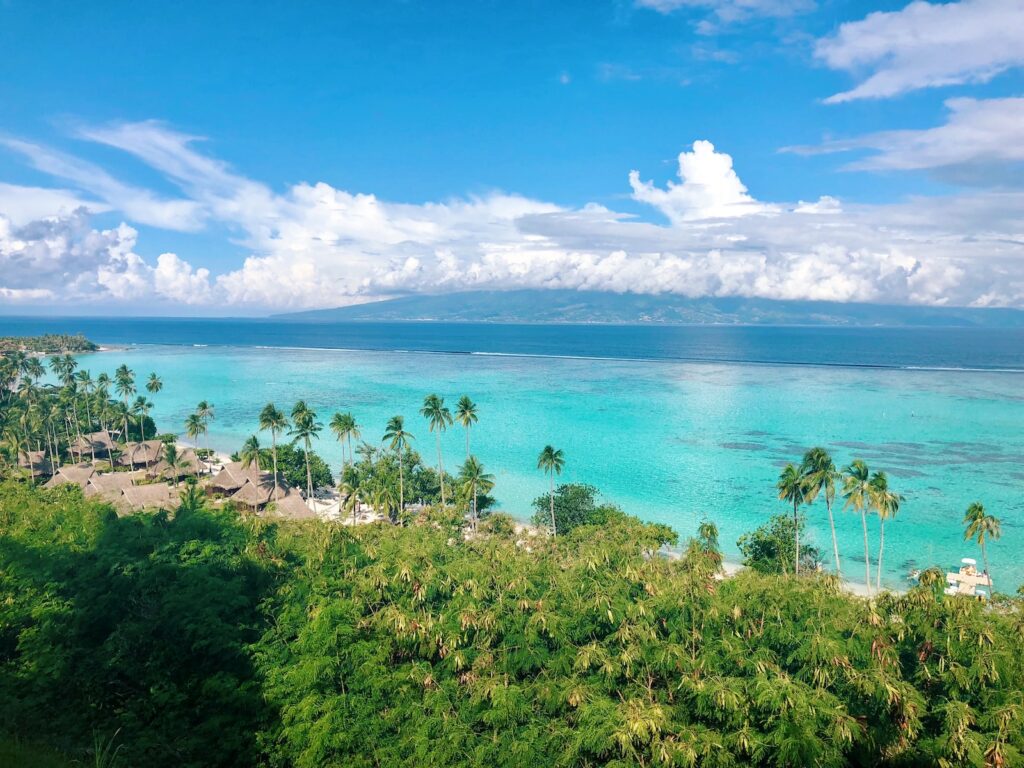 Come away with me to a land with water so clear you can see straight to the ocean floor. Where lush green peaks scrape the sky, crimson hibiscus flowers bob delicately in the breeze, and the humid air fills your lungs with the scent of vanilla and coconut. This is Tahiti—an island paradise tucked away in the South Pacific Ocean that seems almost too good to be true.