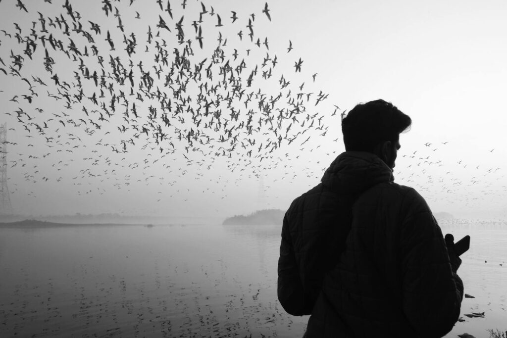 Man in Black Jacket Standing in Front of Body of Water