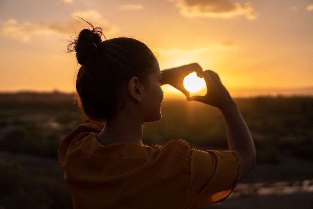 Woman Doing Hand Heart Sign during Golden hour 