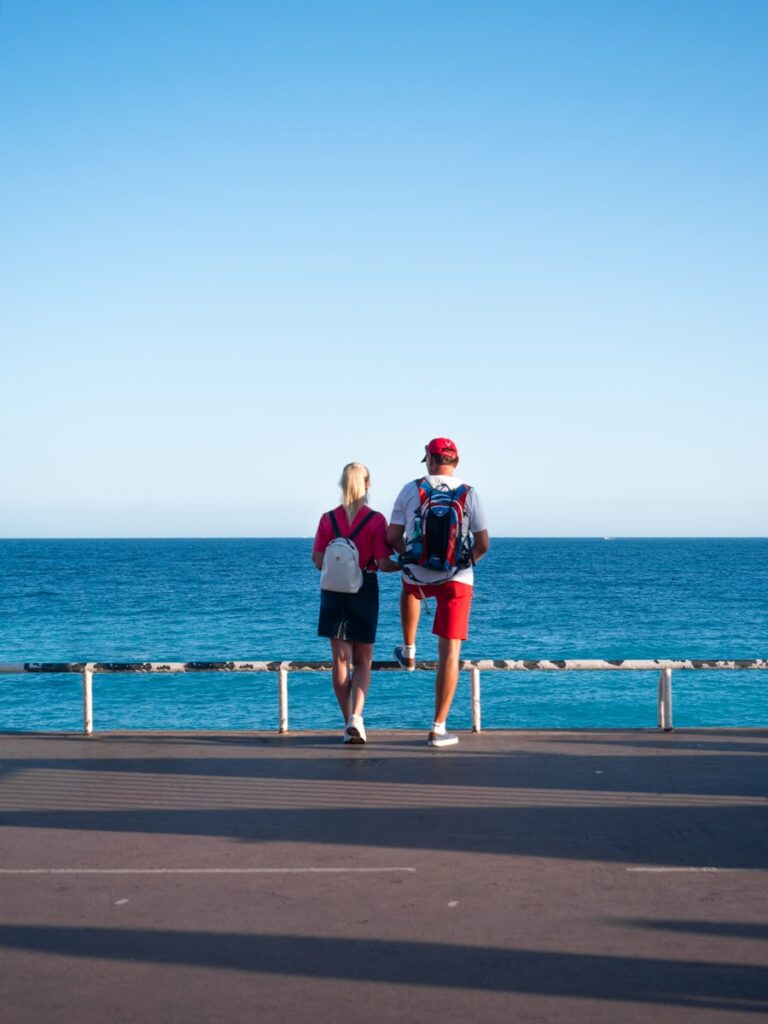 2 men standing on dock near body of water during daytime