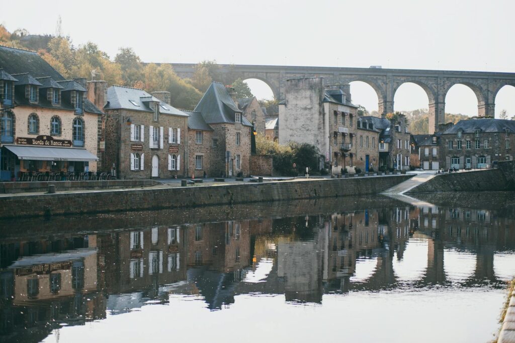 Picturesque scenery of old arched Pont Vieux masonry bridge over river flowing between ancient stone houses of Dinan medieval town located in France