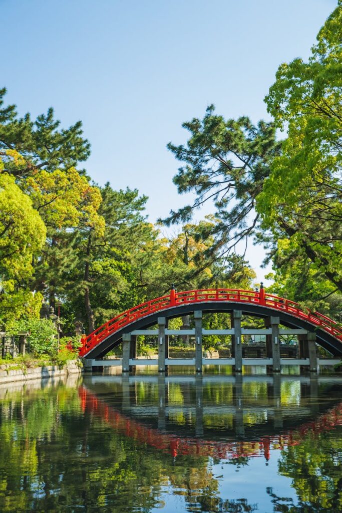 Picturesque view of river with reflection of old oriental footbridge located in green park of Sumiyoshi Grand Shrine Osaka Japan